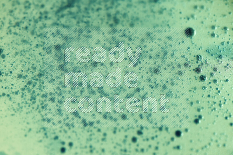 Close-ups of abstract green watercolor drops on oil Surface on green background