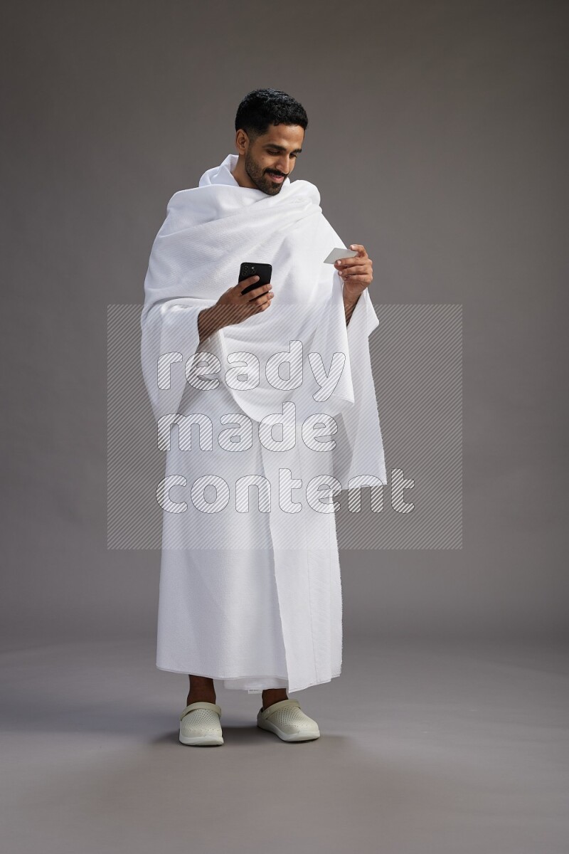 A man wearing Ehram Standing holding ATM card on gray background