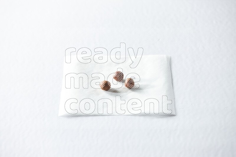 3 peeled hazelnuts on a piece of paper on a white background in different angles