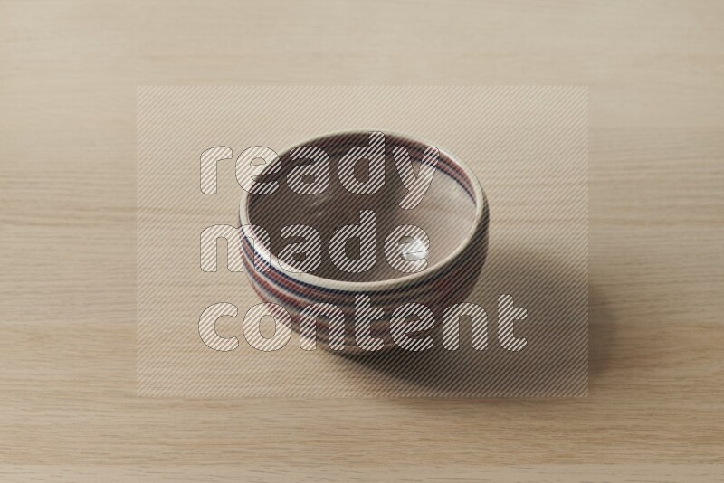 A multicolored pottery bowl on light wooden background