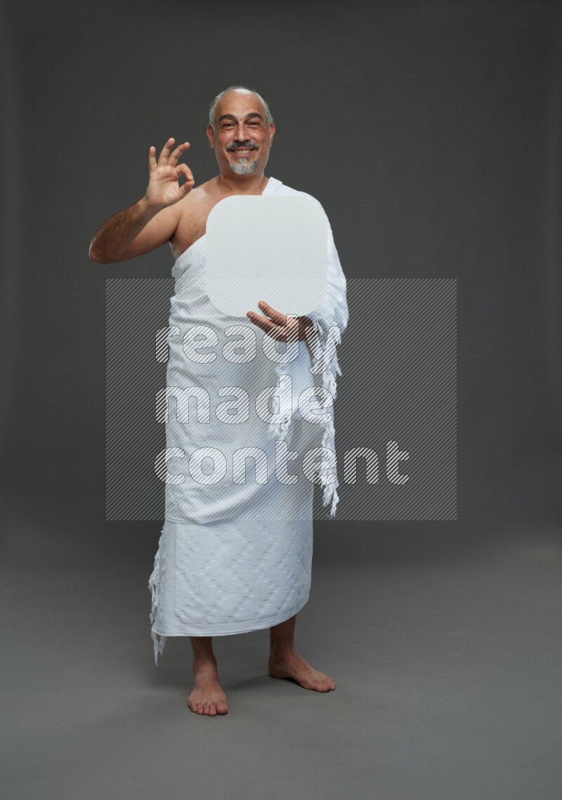A man wearing Ehram Standing holding social media sign on gray background