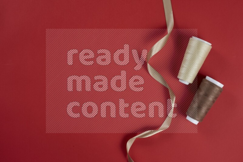 A brown and red collection of sewing and tailoring tools arranged on a red background