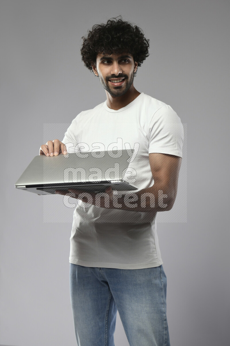 A man wearing casual standing and holding a laptop on white background