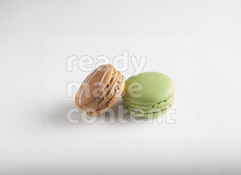 45º Shot of of two assorted Brown Irish Cream, and Green Pistachio macarons on white background