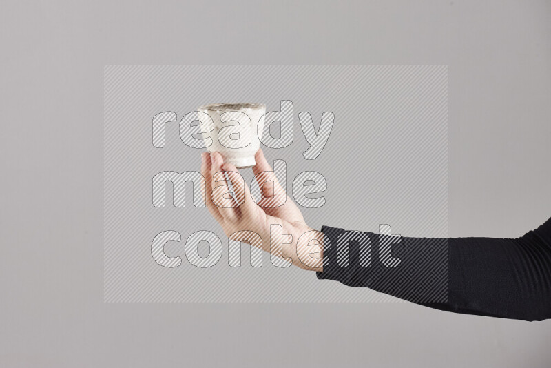 A woman in black abaya holding different pottery essentials in different positions