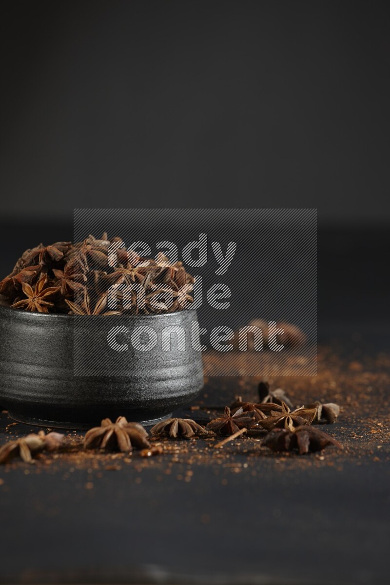 اليانسون النجمي في وعاء أسود مع اليانسون المنثور على خلفية سوداء