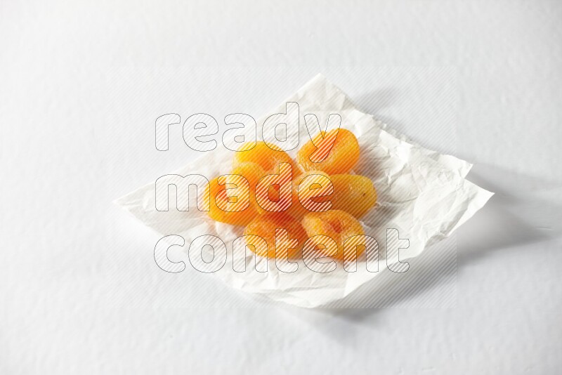 Dried apricots on a crumpled piece of paper on a white background in different angles