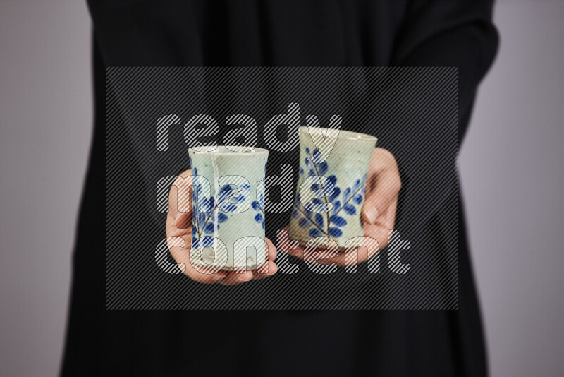 A woman in black abaya holding different pottery essentials in different positions