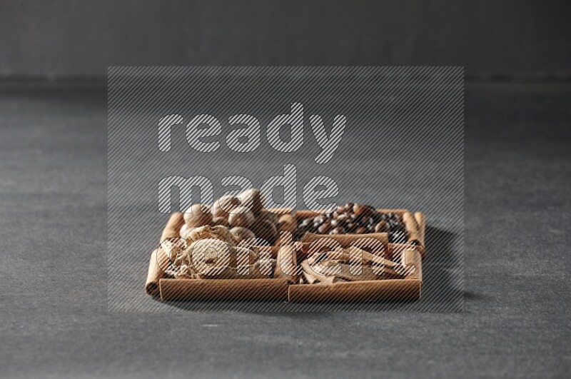 4 squares of cinnamon sticks full of coffee beans, cinnamon, dried ginger and nutmegs on black flooring