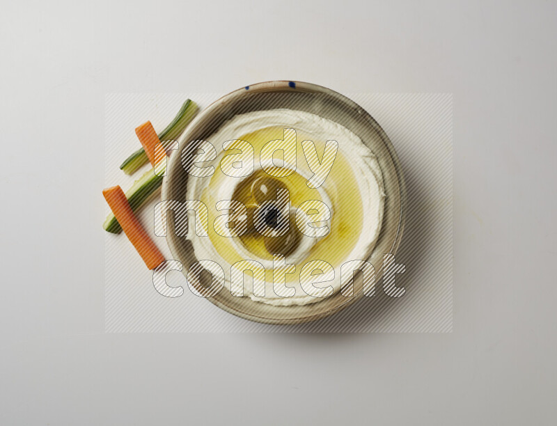 Lebnah garnished with whole olives in a grey pottery plate on a white background