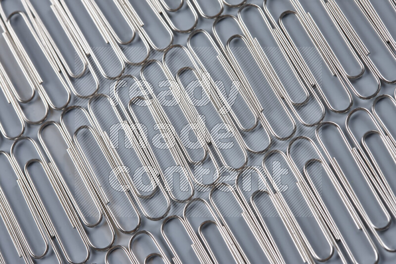 Silver paper clips isolated on a grey background