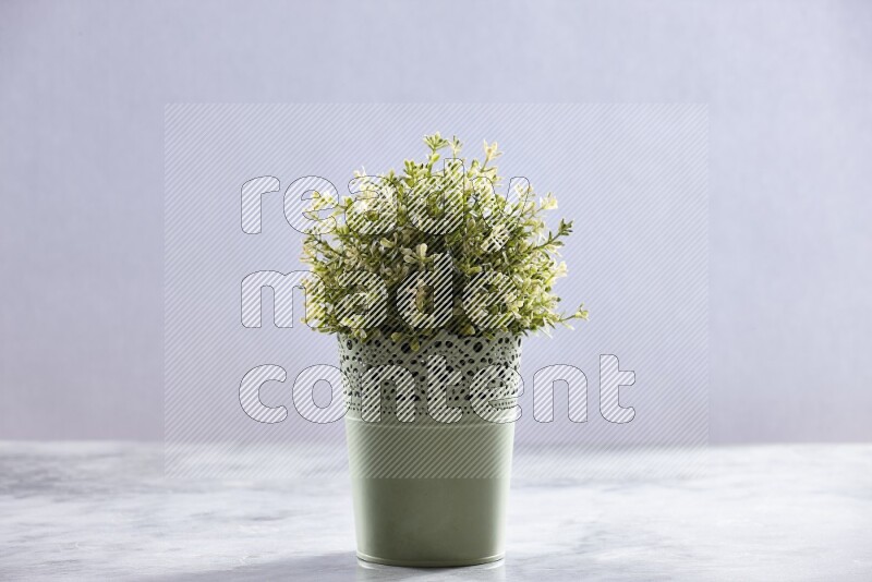 Artificial plant in green decorative pot on grey marble background