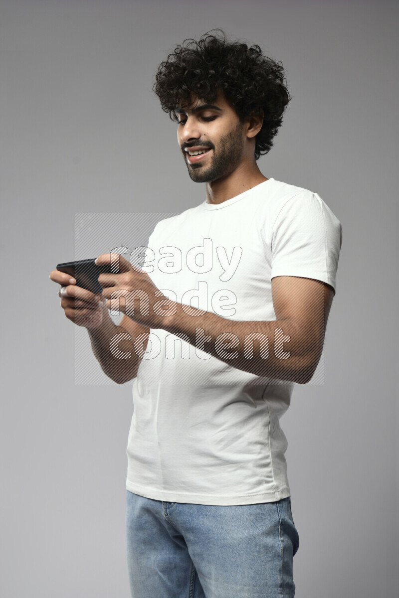 A man wearing casual standing and gaming on the phone on white background