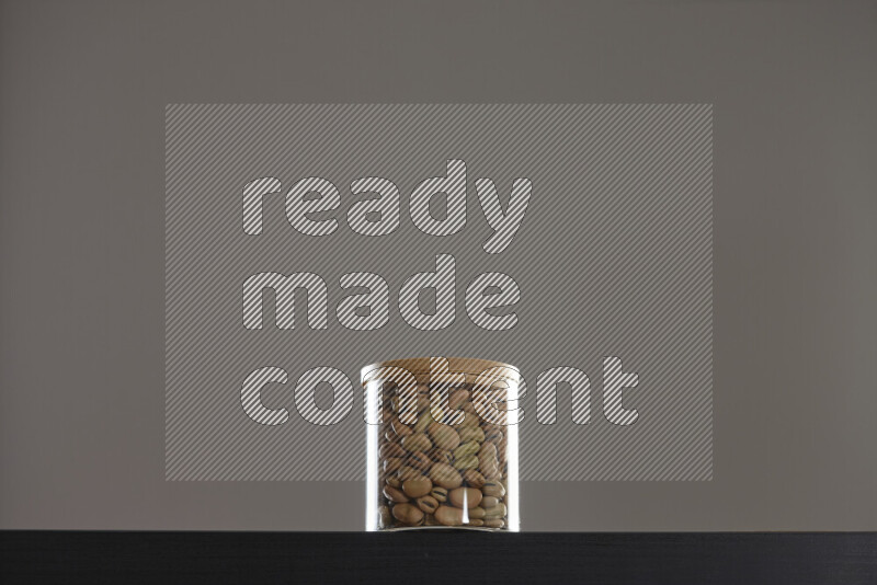 Fava beans in a glass jar on black background