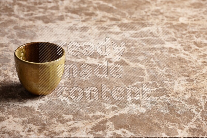 A multicolored pottery cup on beige marble background