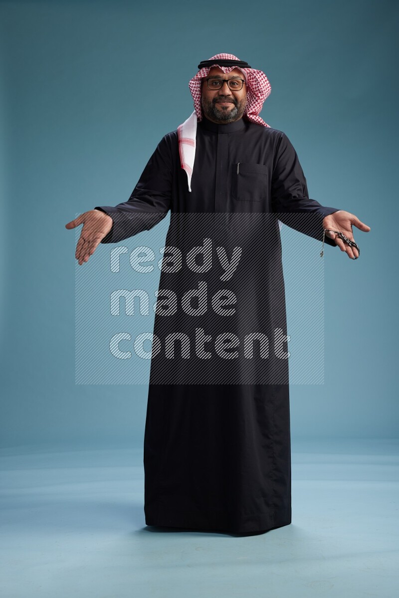 Saudi Man with shimag Standing Interacting with the camera on blue background