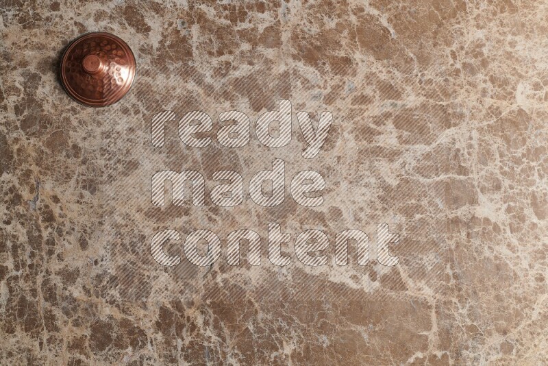A small copper pot on beige marble background
