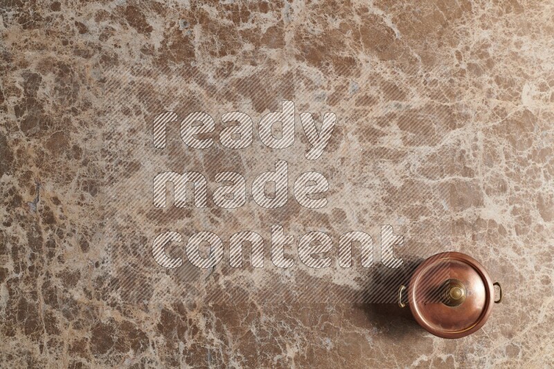 A small copper pot on beige marble background