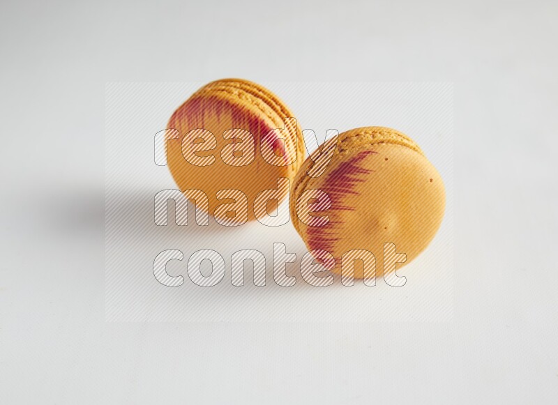 45º Shot of two orange Exotic macarons on white background