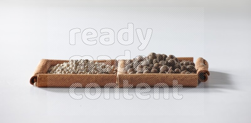 2 squares of cinnamon sticks full of white pepper and allspice on white flooring