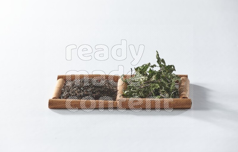 2 squares of cinnamon sticks full of black tea and dried mint leaves on white flooring
