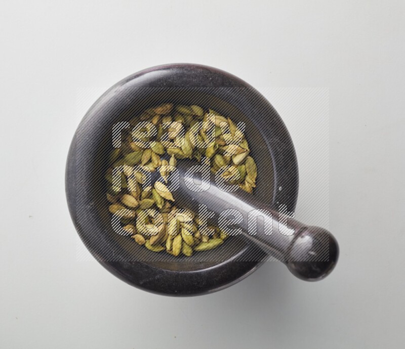 Top-view shot of Cardamon in herbs crusher on white background
