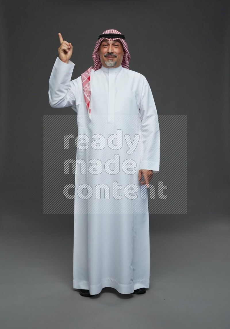 Saudi man with shomag Standing Interacting with the camera on gray background
