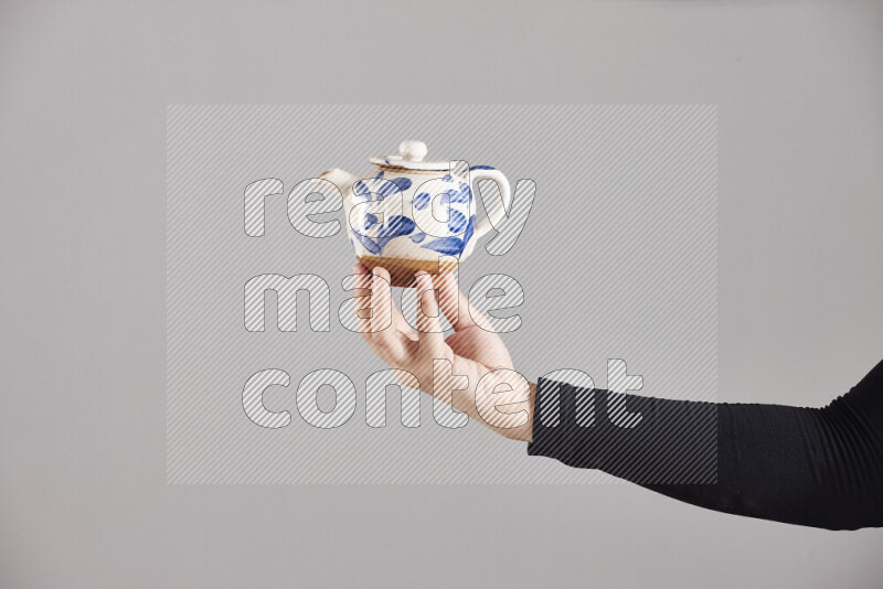 A woman in black abaya holding different pottery essentials in different positions