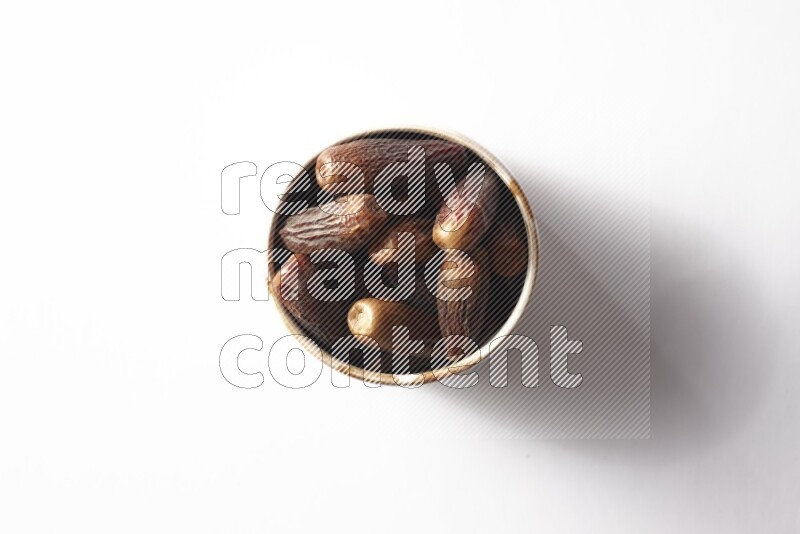 Dates in a beige pottery bowl on white background