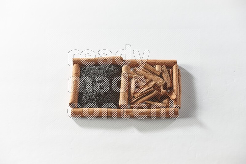 مربعان من أعواد القرفة ممتلئان بحبة البركة السوداء والقرفة علي خلفية بيضاء