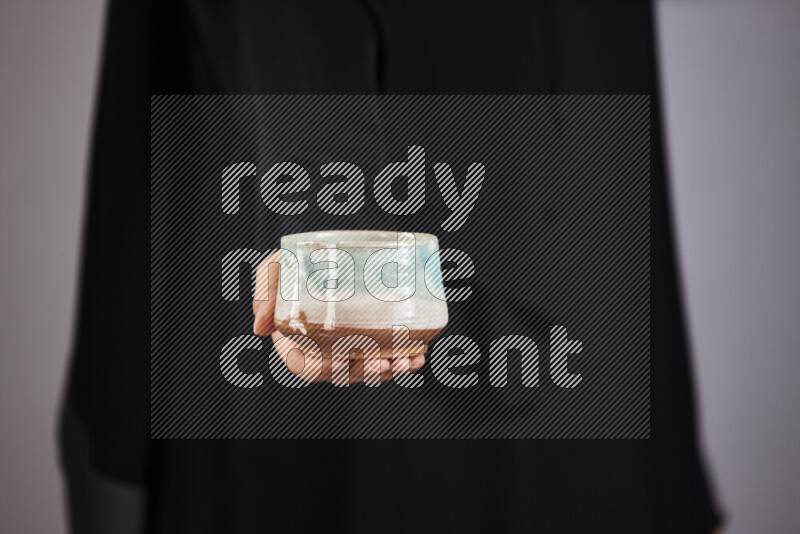 A woman in black abaya holding different pottery essentials in different positions