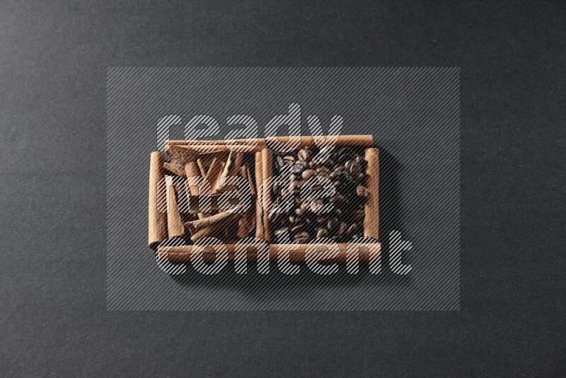 مربعان من أعواد القرفة ممتلئان بحبوب القهوة وقطع من القرفة علي خلفية سوداء