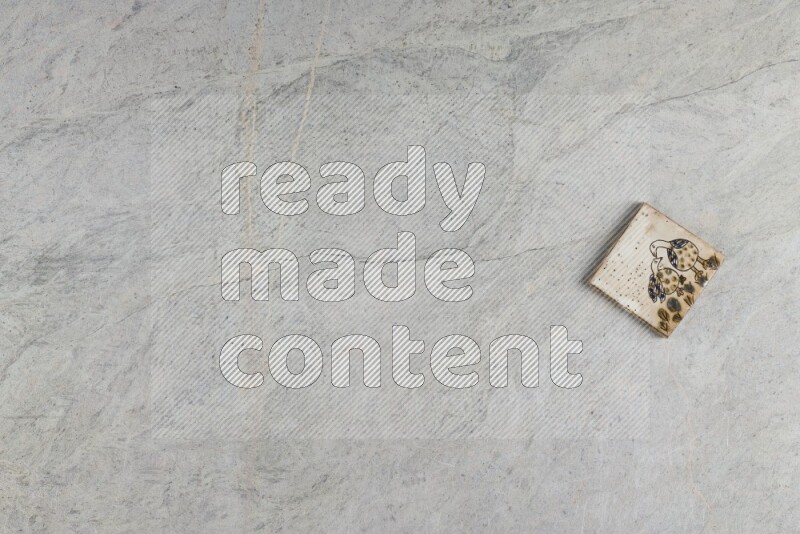 A decorative pottery coaster on grey marble background