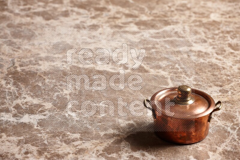A small copper pot on beige marble background