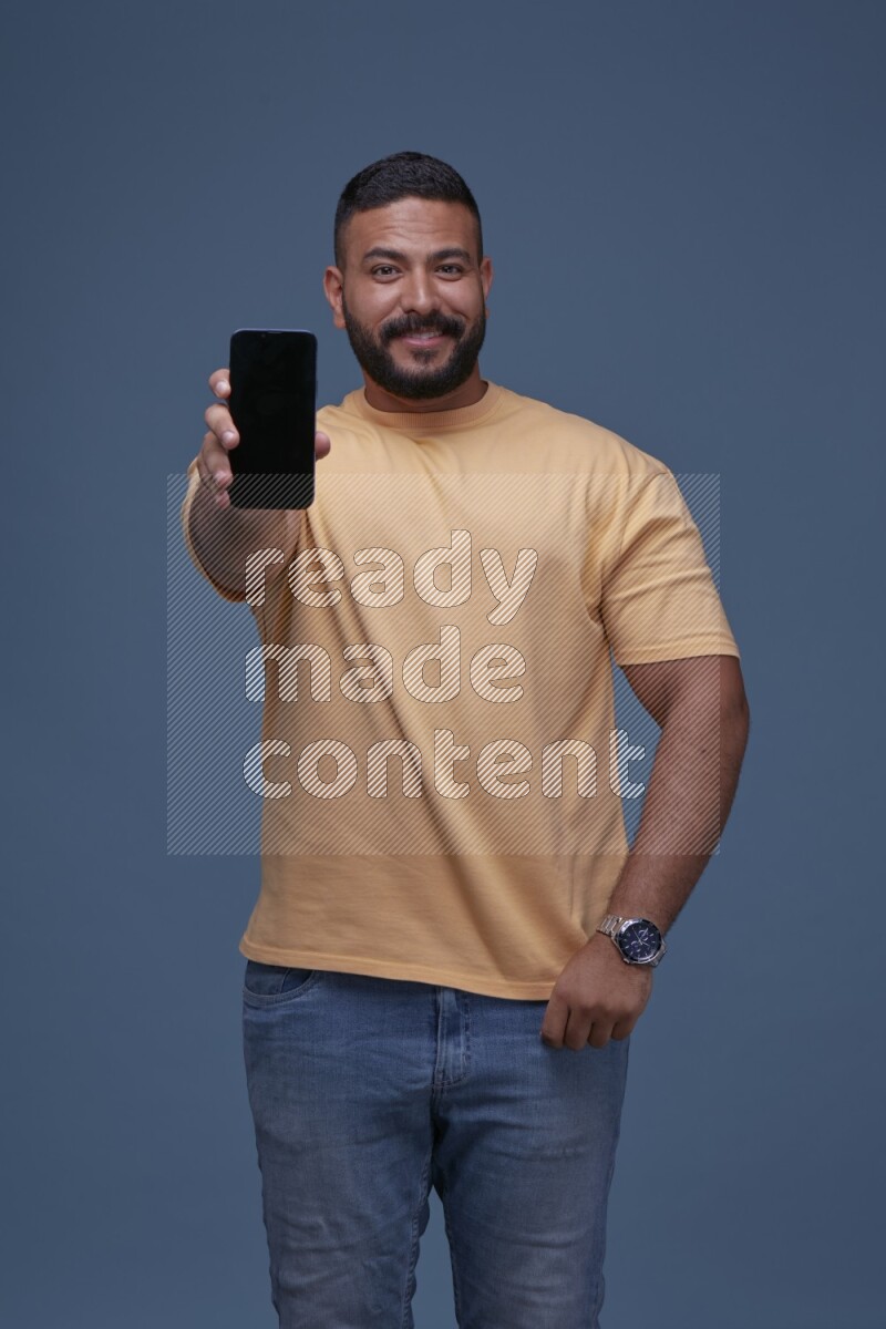 A man Showing His Smart Phone on Blue Background wearing Orange T-shirt