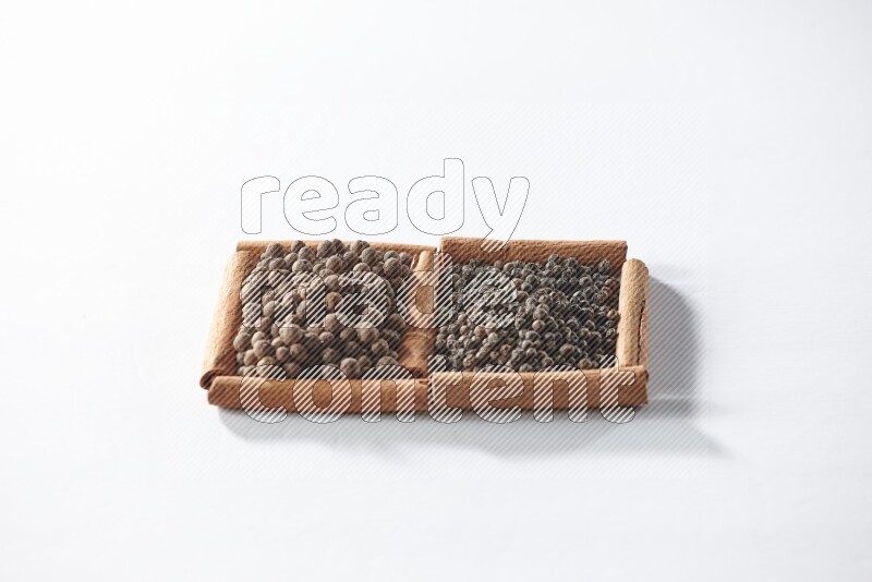 2 squares of cinnamon sticks full of black peppers and allspice on white flooring
