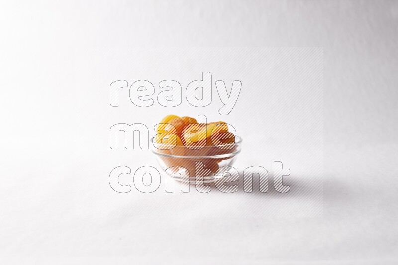 Dried apricots in a glass bowl on white background