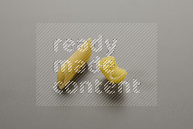 Penne pasta with other types of pasta on grey background