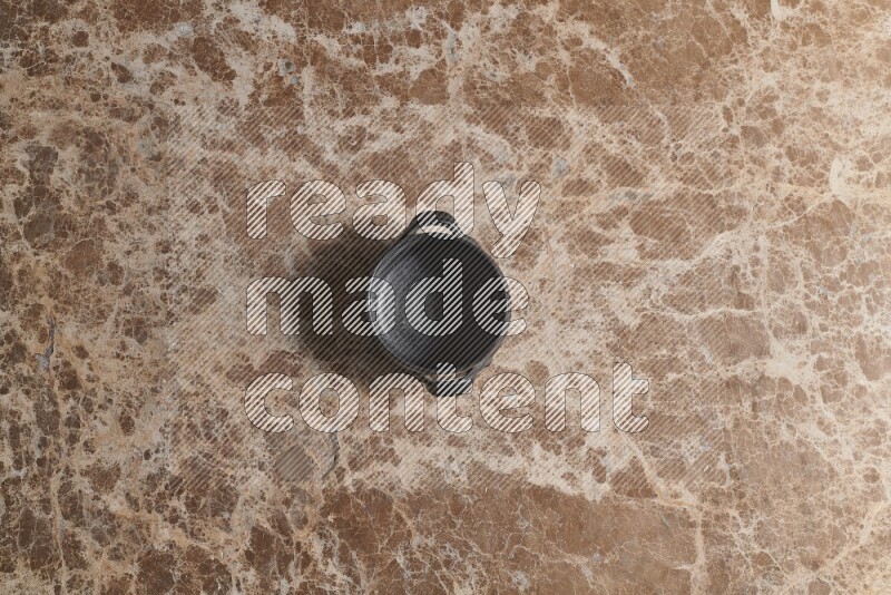 A black pottery bowl on beige marble background
