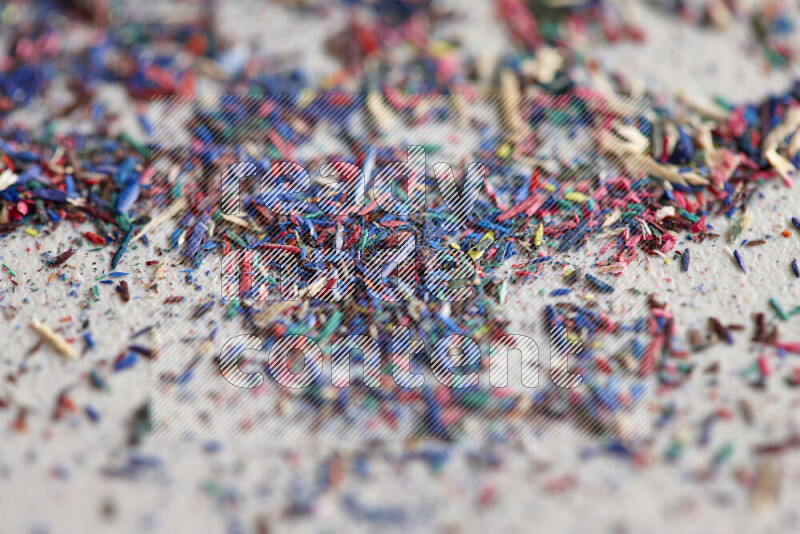 This image showcases a vibrant multicolored pencil shavings scattered on grey background