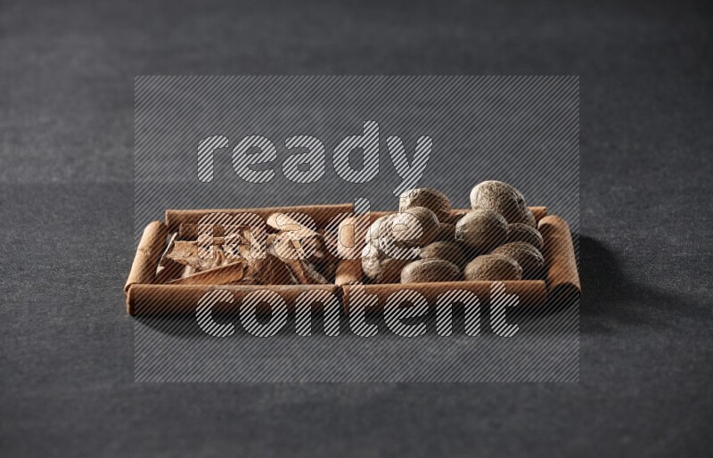 2 squares of cinnamon sticks full of cinnamon and nutmeg on black flooring