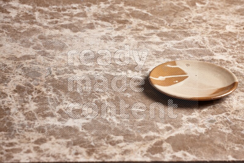 A multicolored pottery plate on beige marble background