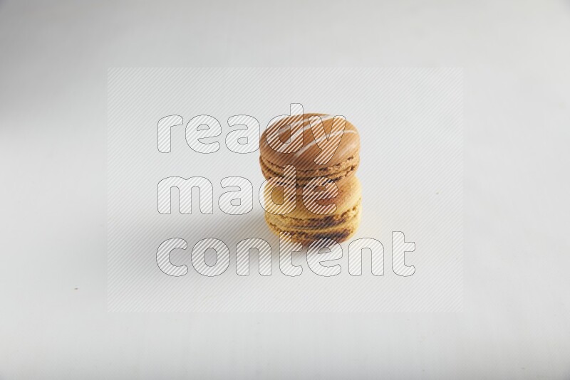 45º Shot of of two assorted Brown Irish Cream, and Yellow Crème Brulée macarons on white background