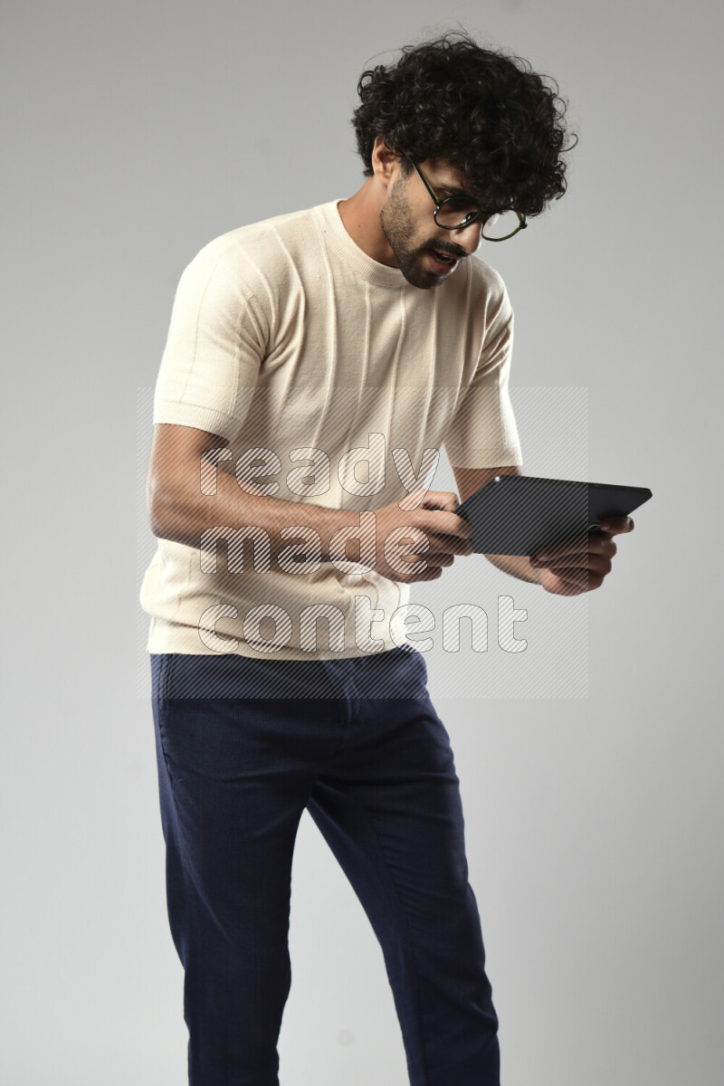 A man wearing casual standing and gaming on a tablet on white background