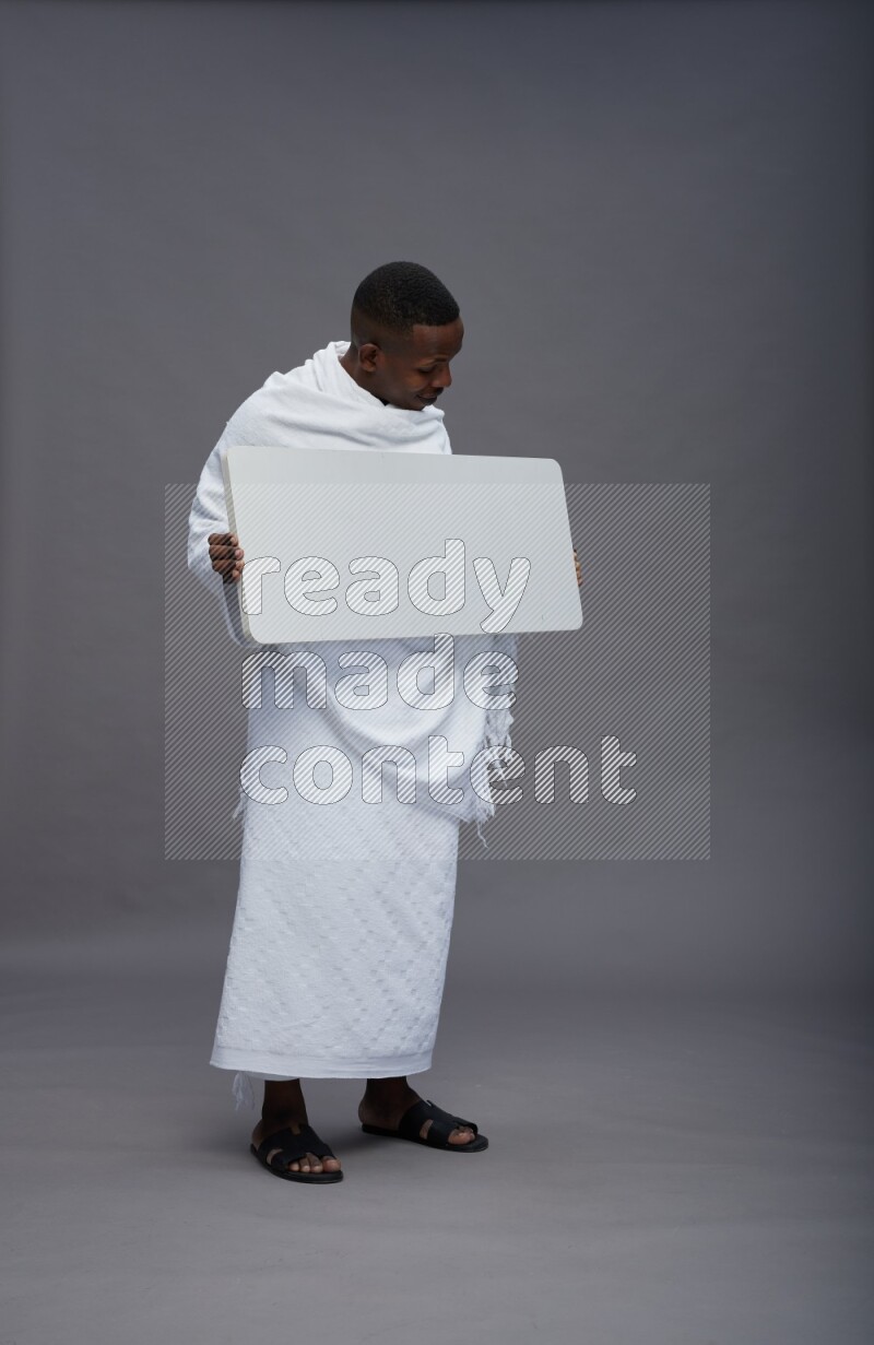 A man wearing Ehram Standing holding board sign on gray background