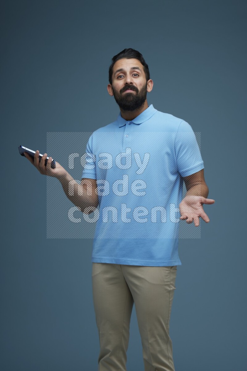 Man posing with a phone in a blue background wearing a Blue shirt