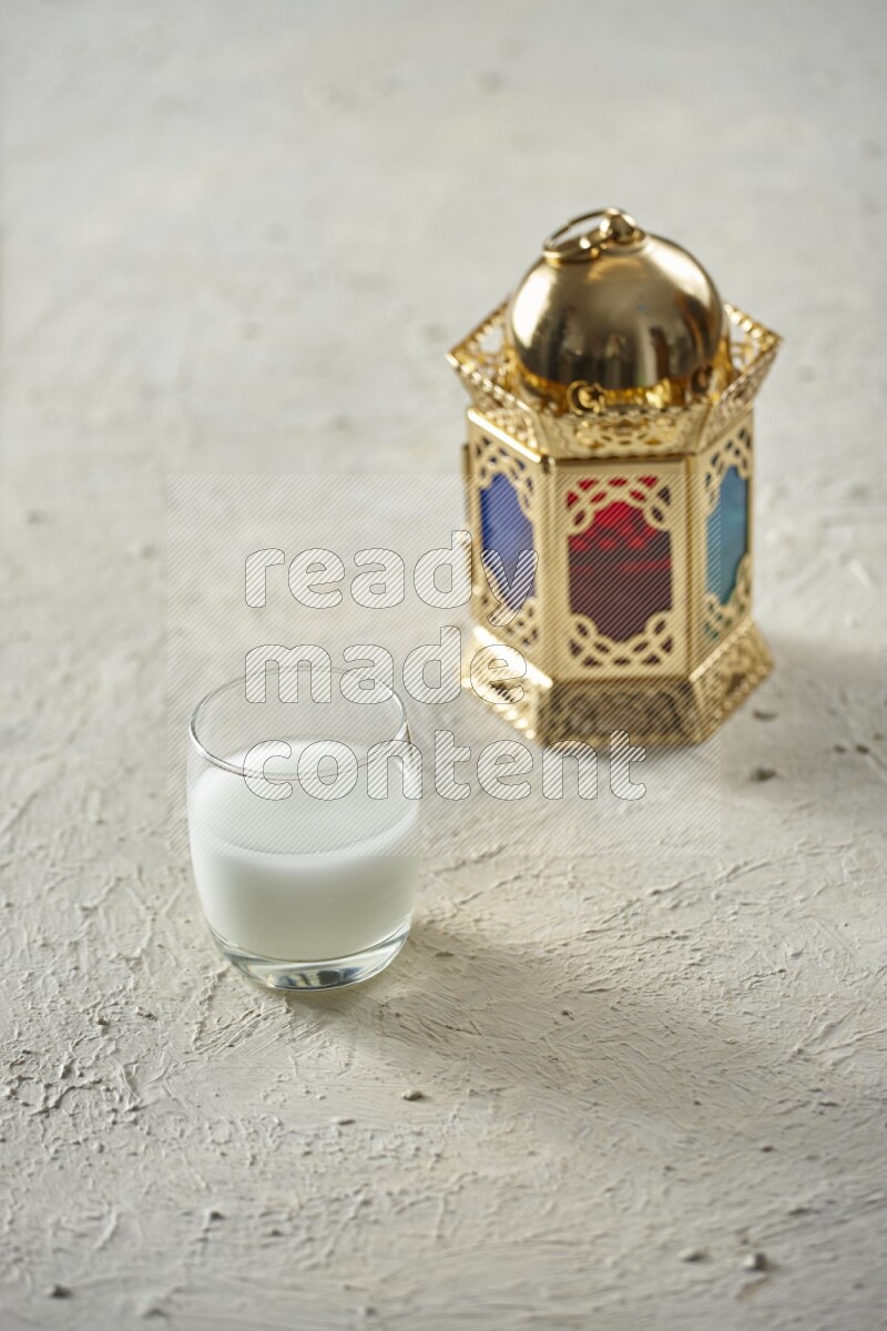 A golden lantern with different drinks, dates, nuts, prayer beads and quran on textured white background