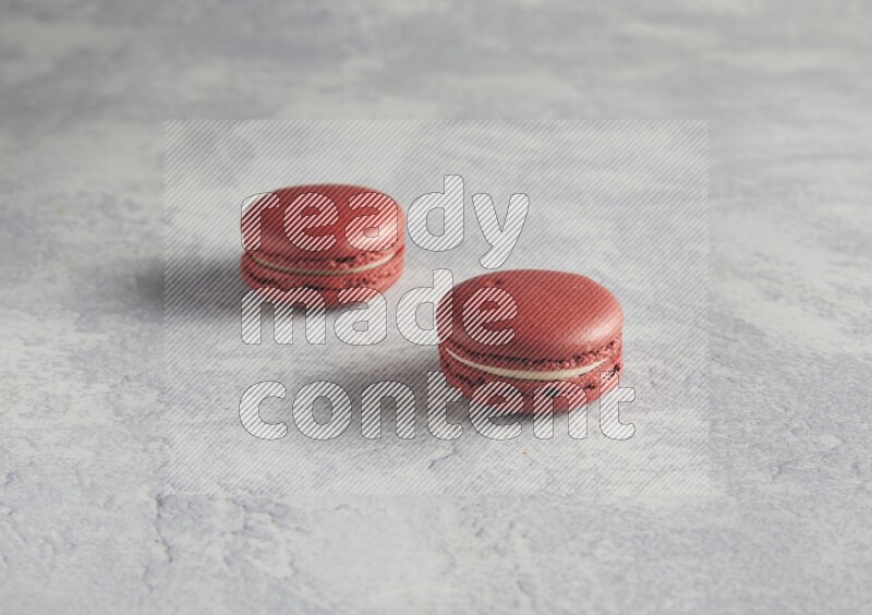 45º Shot of two Red Velvet macarons  on white  marble background