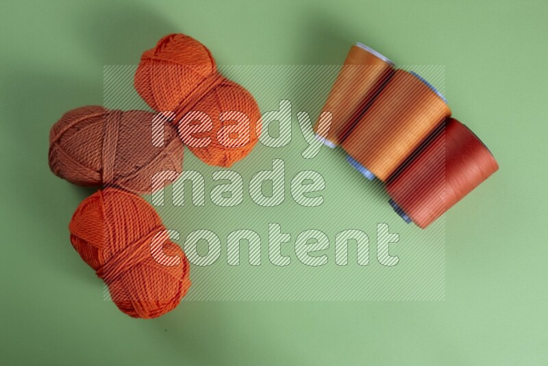 An orange collection of sewing and tailoring tools arranged on a green background