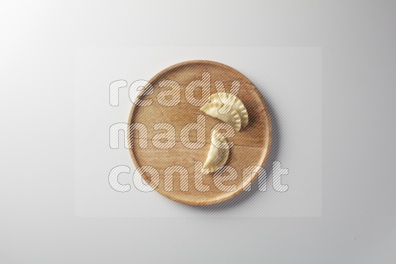 Three Sambosas on a wooden round plate on a white background